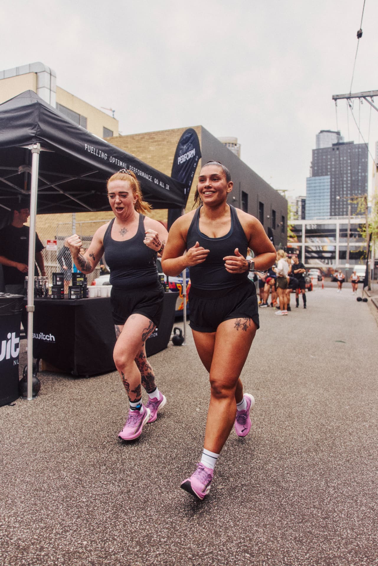 Teammates running side by side past the Switch tent